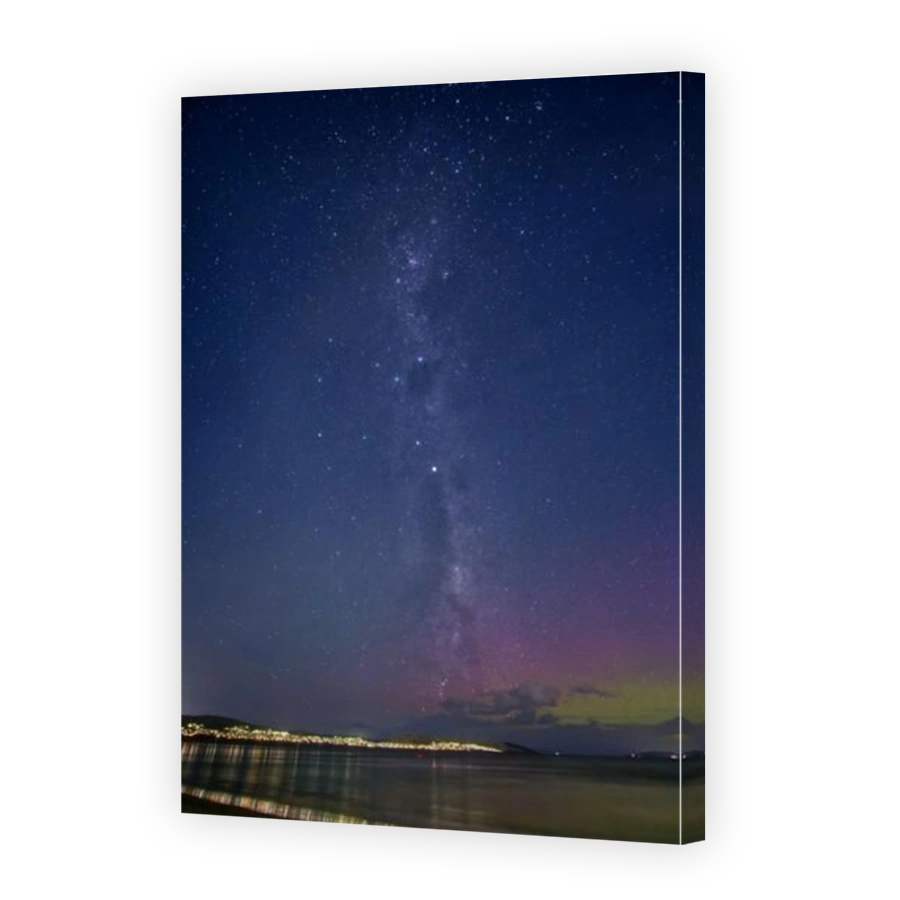 Milky way rising in clear sky with stars and city lights reflected in the Derwent river with Aurora Australis Hobart Tasmania Australia