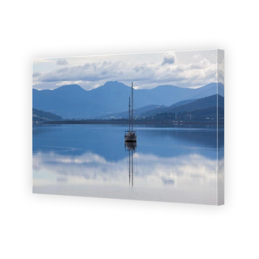 Sailboat reflecting in calm waters of Huon River. Huon Valley, Tasmania, Australia.