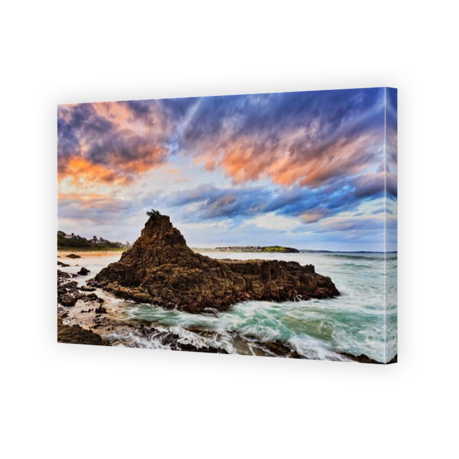 Colourful sunset in clouds and waters around sandstone cliffs off Bombo beach in Kiama of Australia - Pacific coast.