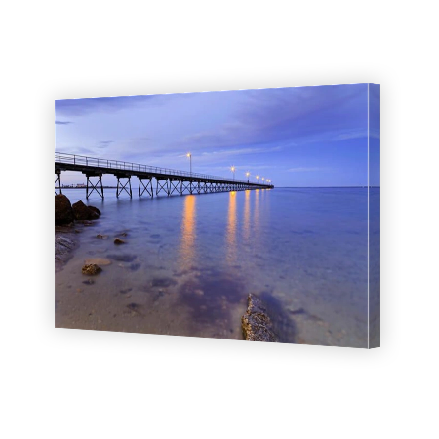 Clean transparent seabed at low tide in Ceduna bay of Great Australian Bight at sunrise. Historic fishing timber jetty with elec