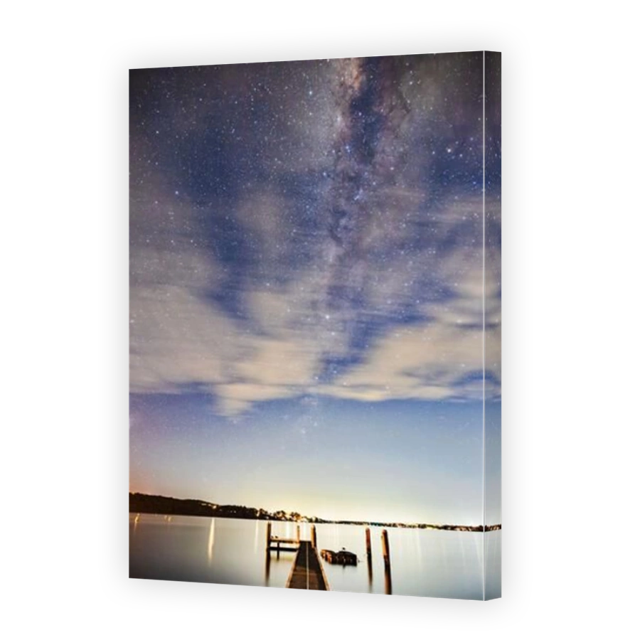 Milky way behind blurred clouds over Lake Macquarie in Australia - night sky stargazing.