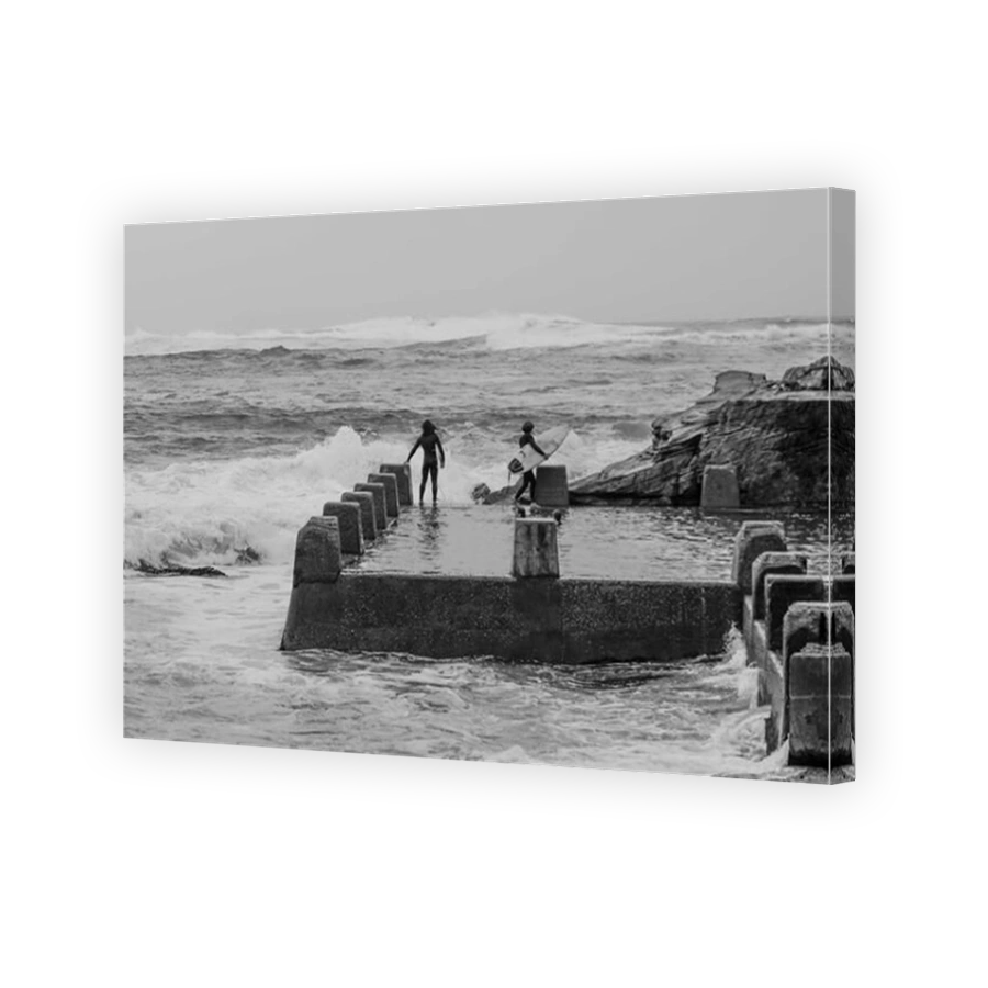 A surfer prepare to enter rough seas from Coogee ocean pool.