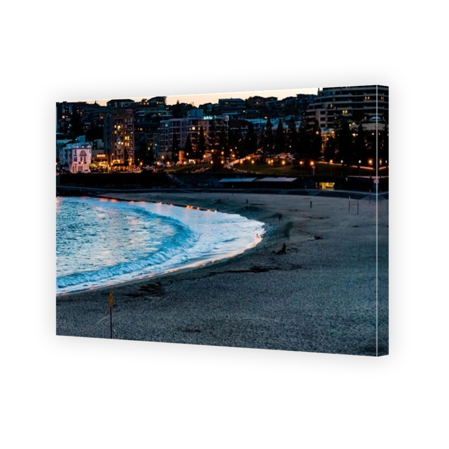 Panorama of beach ocean and city lights, Coogee Beach, Sydney, Australia. Evening cityscape of calm beach lights of buildings reflecting on ocean.
