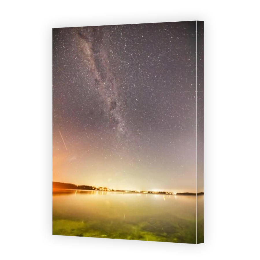 Waterfront of Lake Macquarie reflecting starry night Milky Way galaxy over Southern Hemisphere in Australia.