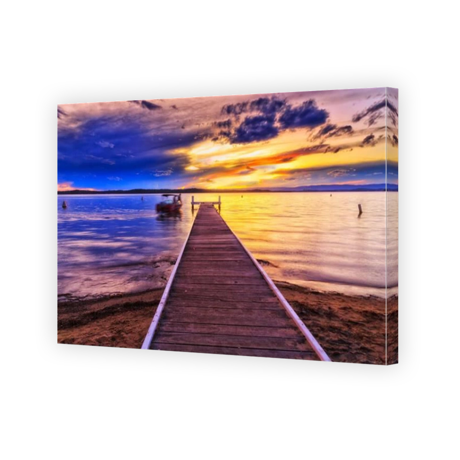 Fishing boat floating at timber jetty off Murrays beach resort beach on Lake Macquarie at sunset.