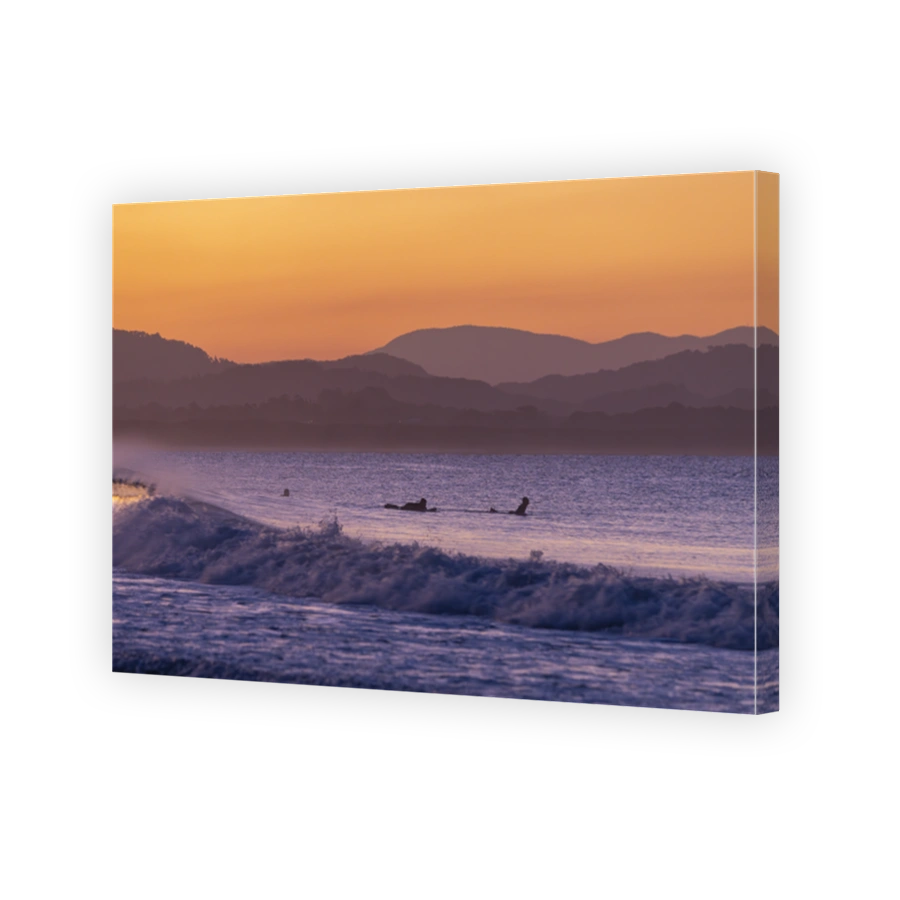 Sunset view of surfers in silhouette along the Belongil Beach area in Byron Bay, New South Wales, Australia