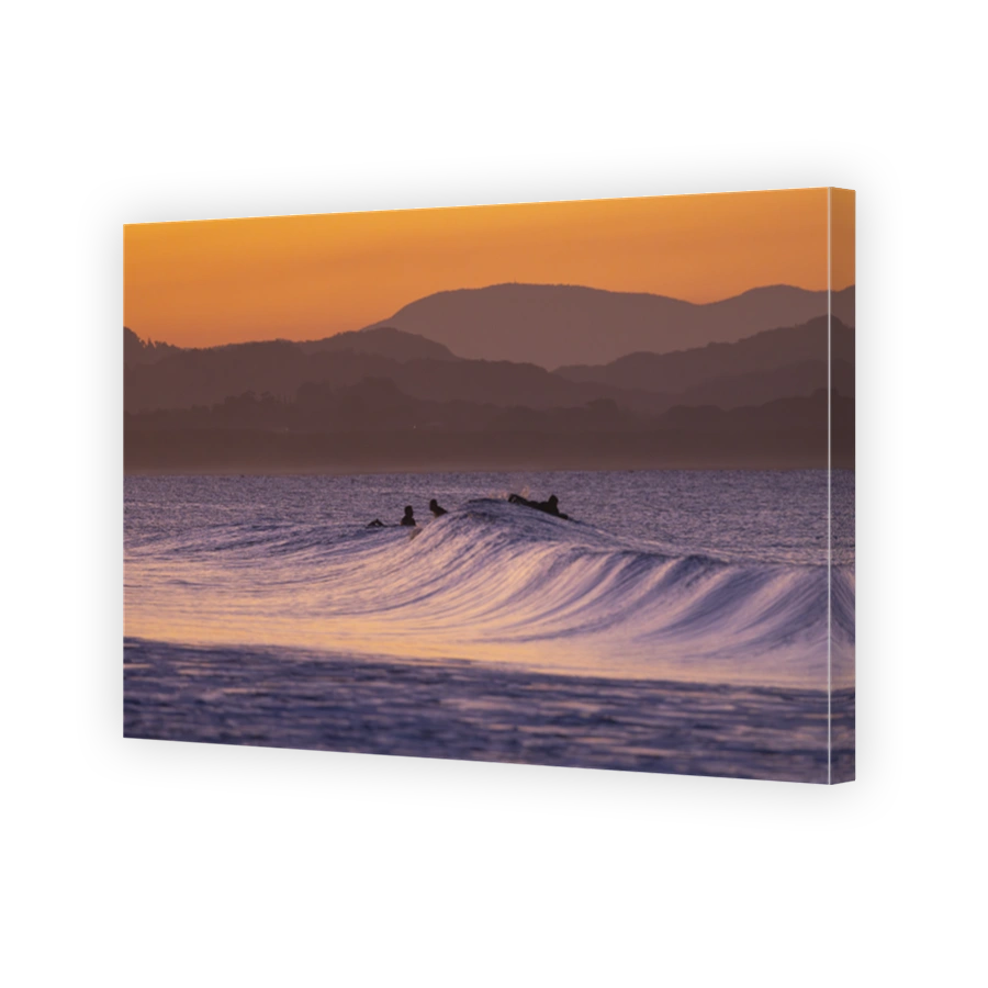 Sunset view of surfers in silhouette along the Belongil Beach area in Byron Bay, New South Wales, Australia