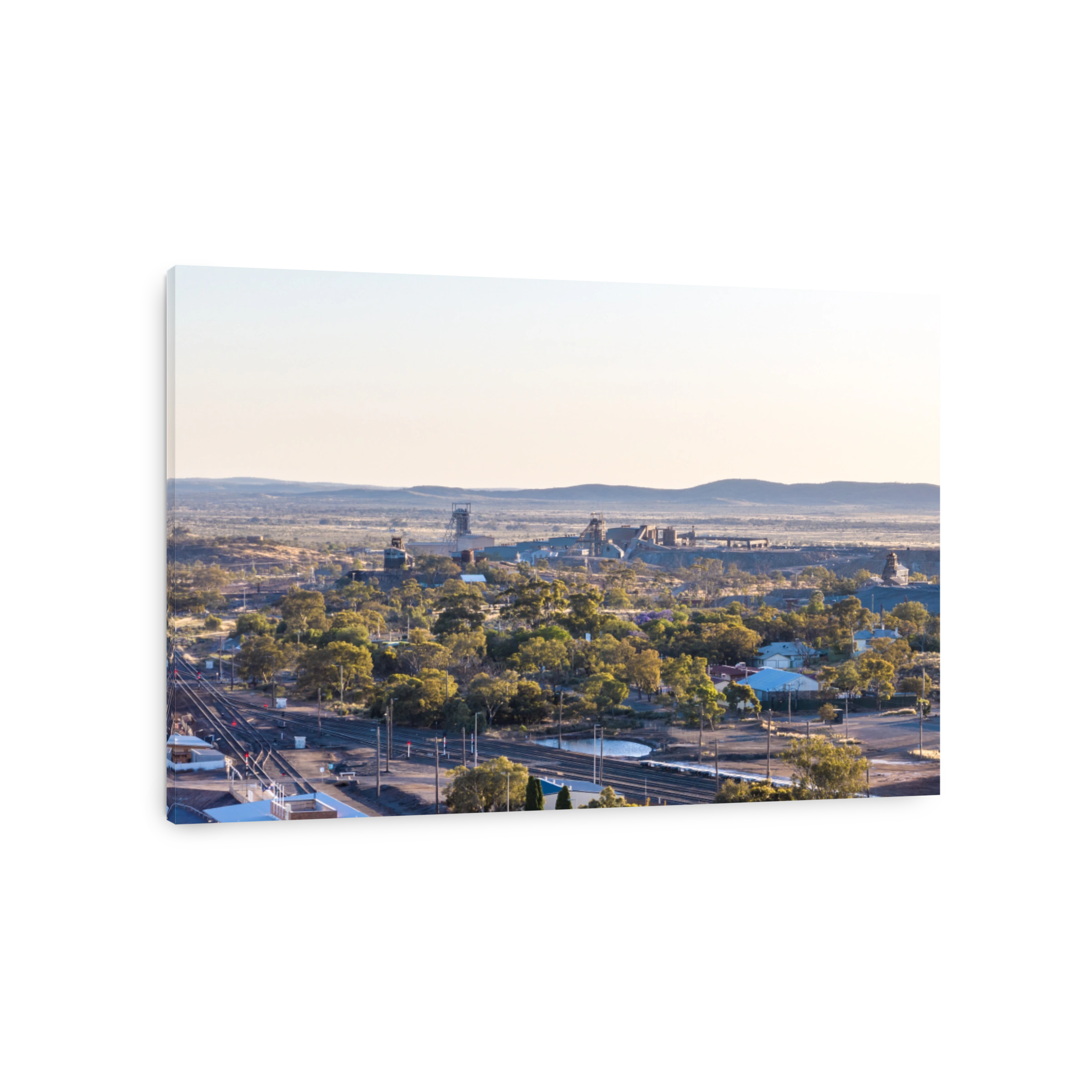 Early morning aerial zoom view of mine shafts and a beneficiation or processing plant located in Broken Hill, New South Wales, Australia. Train tracks in the foreground, mountain range in the back.