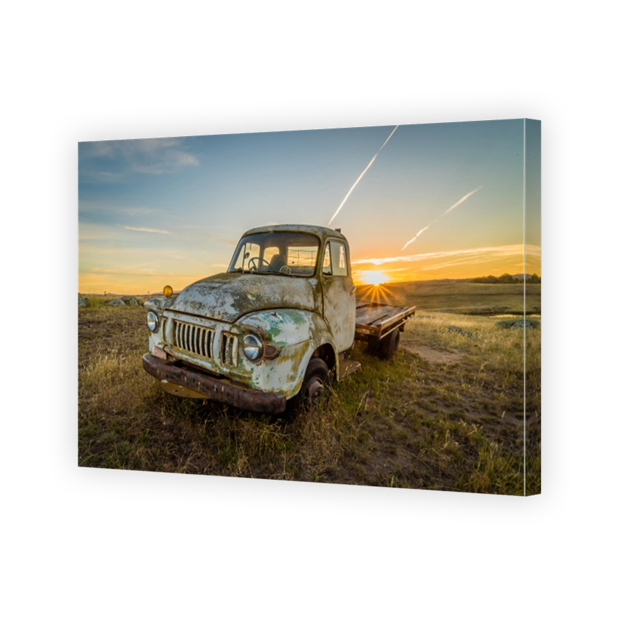 Old rusty car in a field in Australia with sunset in the background