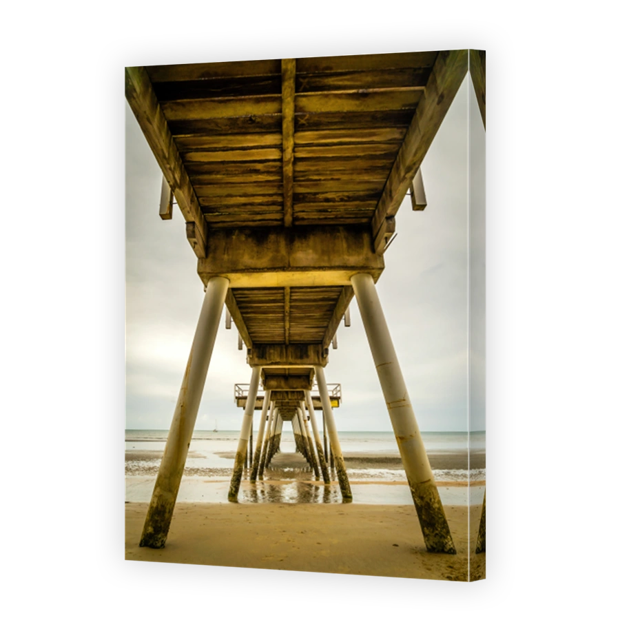 Symmetric view from below a pier over the ocean in Australia