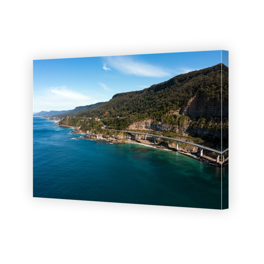Aerial view of the beautiful Illawarra coastal escarpment featuring the famous Sea Cliff Bridge. Captured from high above a clear blue pacific ocean looking south along the winding bridge to Wollongong.