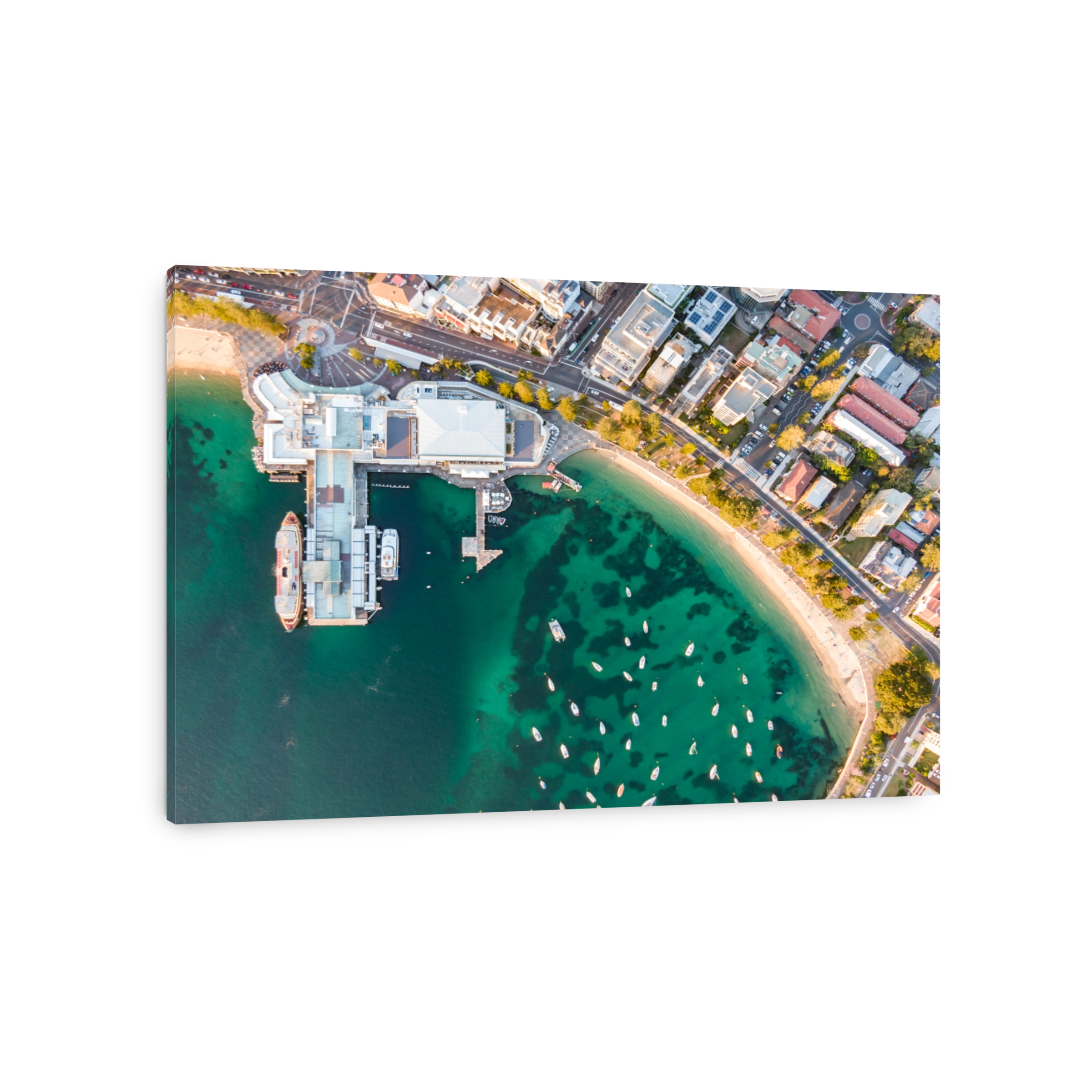 Vertical bird's eye aerial evening drone view of Manly wharf, part of the oceanside suburb of Manly, Sydney, New South Wales, Australia. Two ferries docked at the wharf.