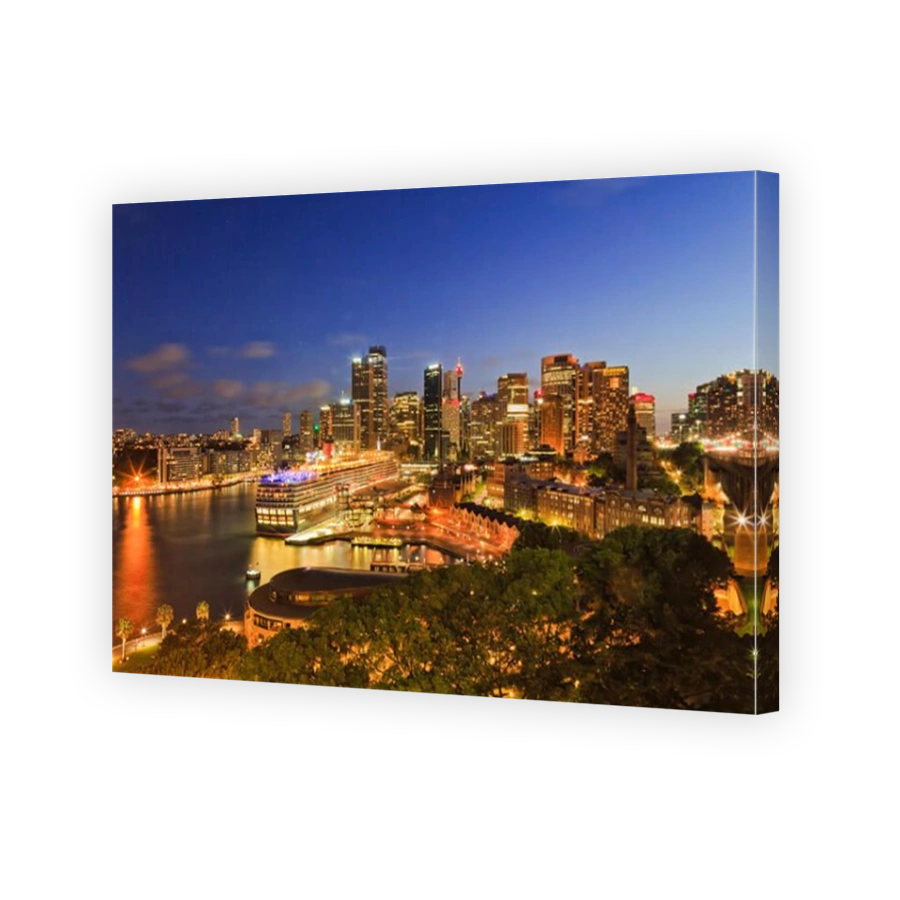 Sydney Circular Quay of Harbour with surrounding city CBD high-rise towers brightly illuminated at sunset with overseas passenge
