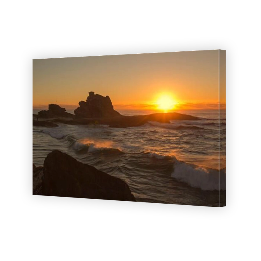 Panoramic image of fiery sunrise over the Pacific Ocean and jagged rocks beside beach in sheltered bay at Nambucca Heads NSW Australia