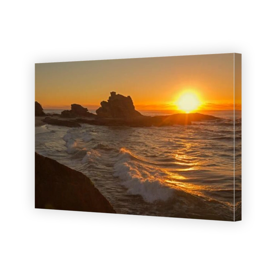 Panoramic image of fiery sunrise over the Pacific Ocean and jagged rocks beside beach in sheltered bay at Nambucca Heads NSW Australia