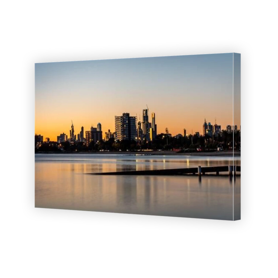 The reflections of the melbourne city skyline at dusk in the still water at st kilda beach