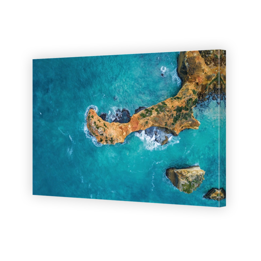 Looking down at turquoise ocean waves breaking over rocks - aerial view