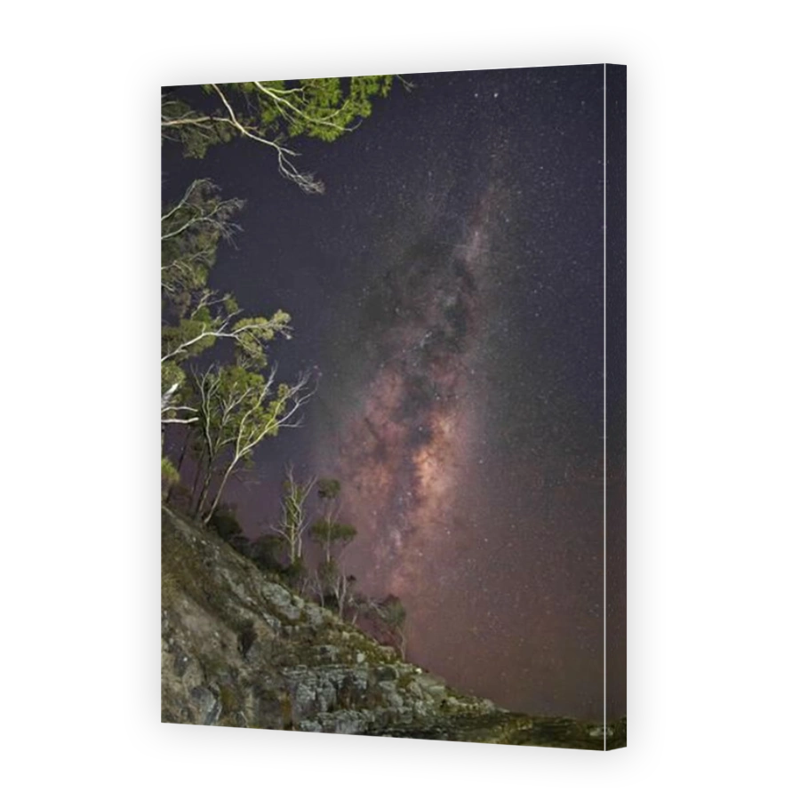 Galactic bulge of Milky Way stars at night with light painting of cliff and trees at Alum Cliffs, Kingston, Hobart, Tasmania, Australia