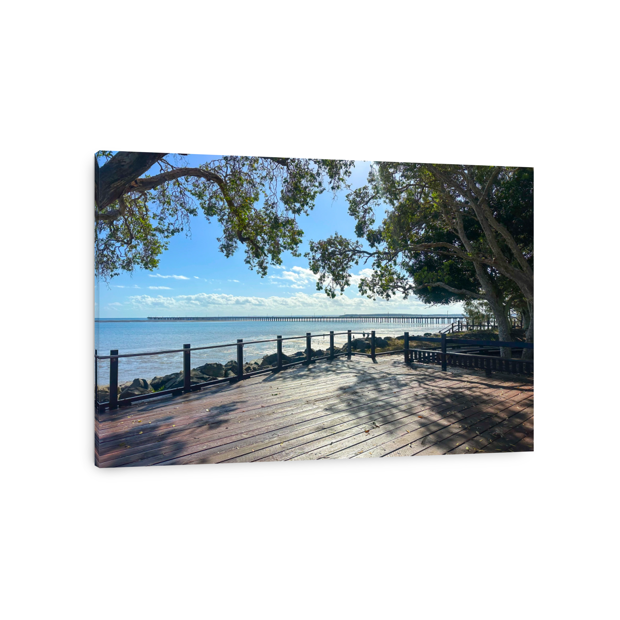 Looking out over a timber viewing platform to calm waters and Urangan Pier in the distance.  Calm water.  Blue skies.  Hervey Bay Queensland Australia