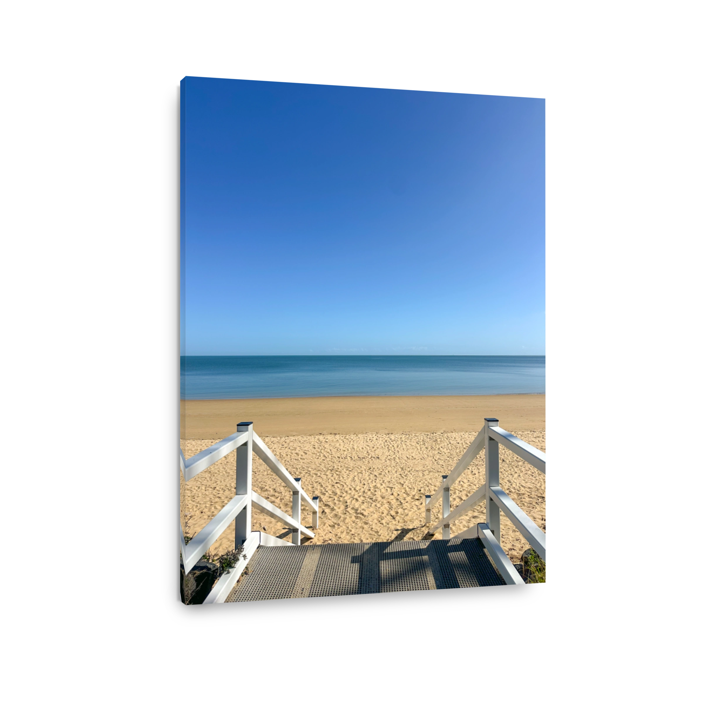 Looking out from stairs with white railings down onto the sandy beach.  Blue calm water and blue skies.  Hervey Bay Queensland Australia