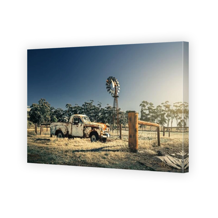 Kapunda, South Australia - June 17, 2017: Abandoned rusty Classic Holden FJ Ute parked next to an old windmill viewed from the road