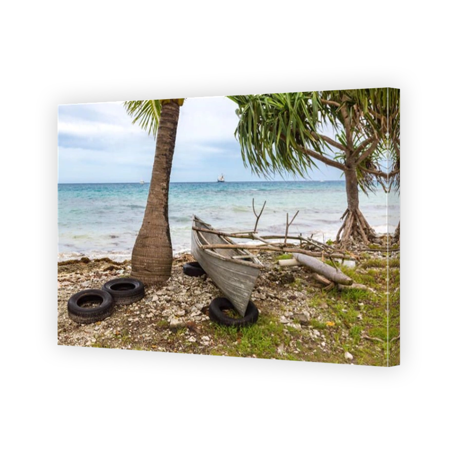 Traditional Polynesian outrigger canoe lies atop of old tires on a rocky shore of Funafuti atoll lagoon under pandanus. Tuvalu, Polynesia, Oceania