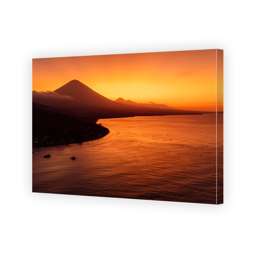 Drone view panorama of coastline with silhouette of volcano and sunset with quiet sea in Bali.