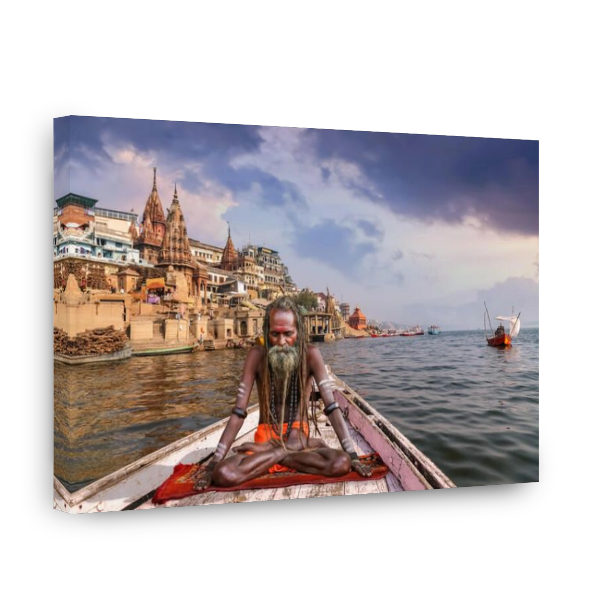 Sadhu baba in meditation posture on a wooden boat on river Ganges overlooking the Varanasi city at sunset