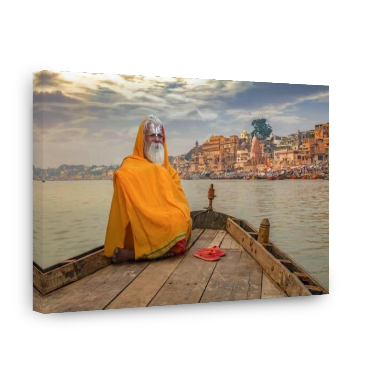 Sadhu baba in meditation on a wooden boat overlooking the historic Varanasi city and Ganges river ghats, India.