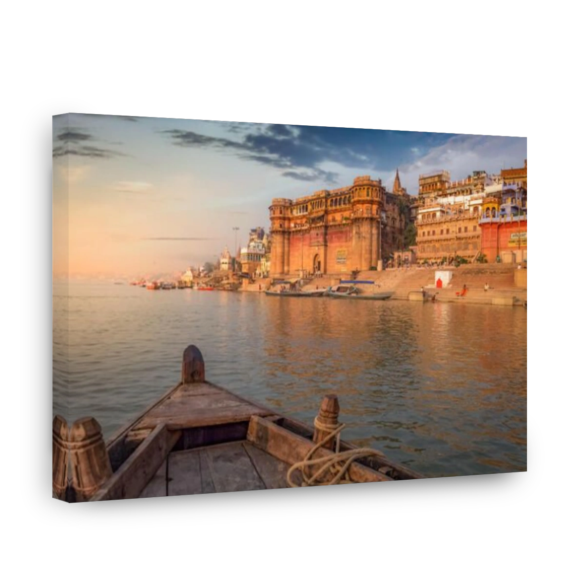Varanasi Ganges river ghat with ancient architectural buildings and temples as viewed from a boat on the river at sunset.