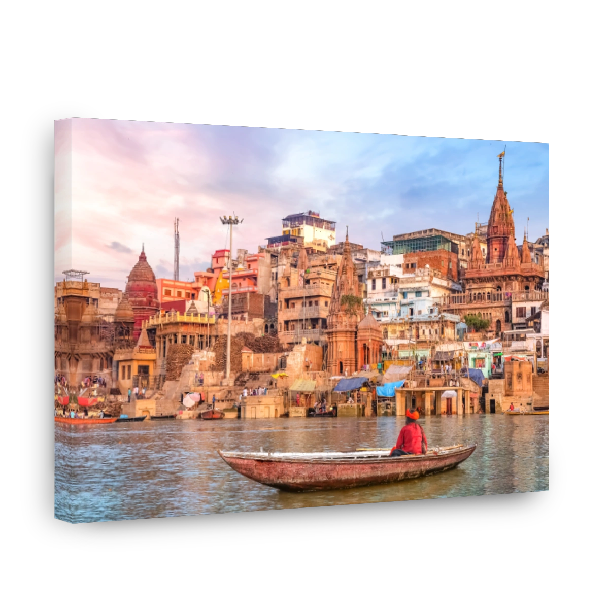 Hindu sadhu sitting on a boat overlooking Varanasi city architecture at sunset