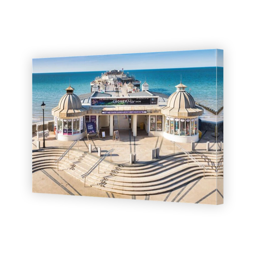 22 June 2019: Cromer, Norfolk, UK - The pier, from above, showing the entrance and steps, on a beautiful summer evening. In the distance, people strol