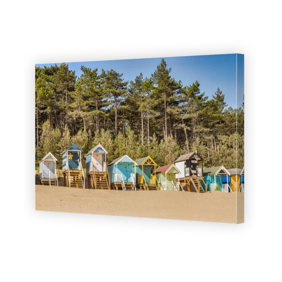 29 June 2019: Wells-Next-The-Sea, Norfolk, England, UK - Bathing huts on the beach, pine trees behind.