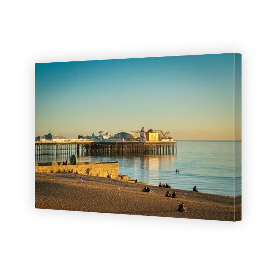 13 January 2022: Brighton, East Sussex, UK - People sitting on Brighton Beach at sunset on a clear winter evening, near the Doughnut Groyne and...