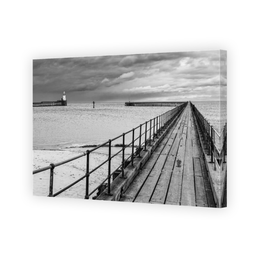 The two old wooden piers protecting the entrance to the Port of Blyth in Northumberland, with the pretty lighthouse on the north pier in the distance.