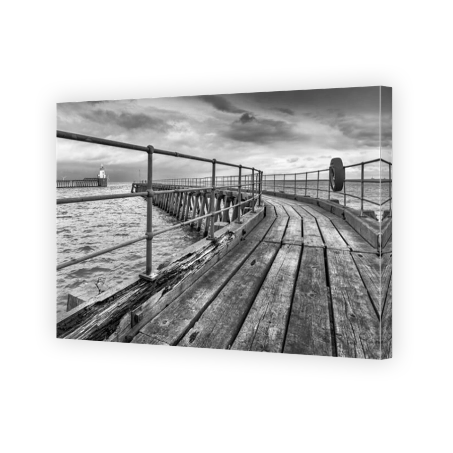 The old wooden south pier at the entrance to the Port of Blyth in Northumberland, with the pretty lighthouse on the north pier in the distance.