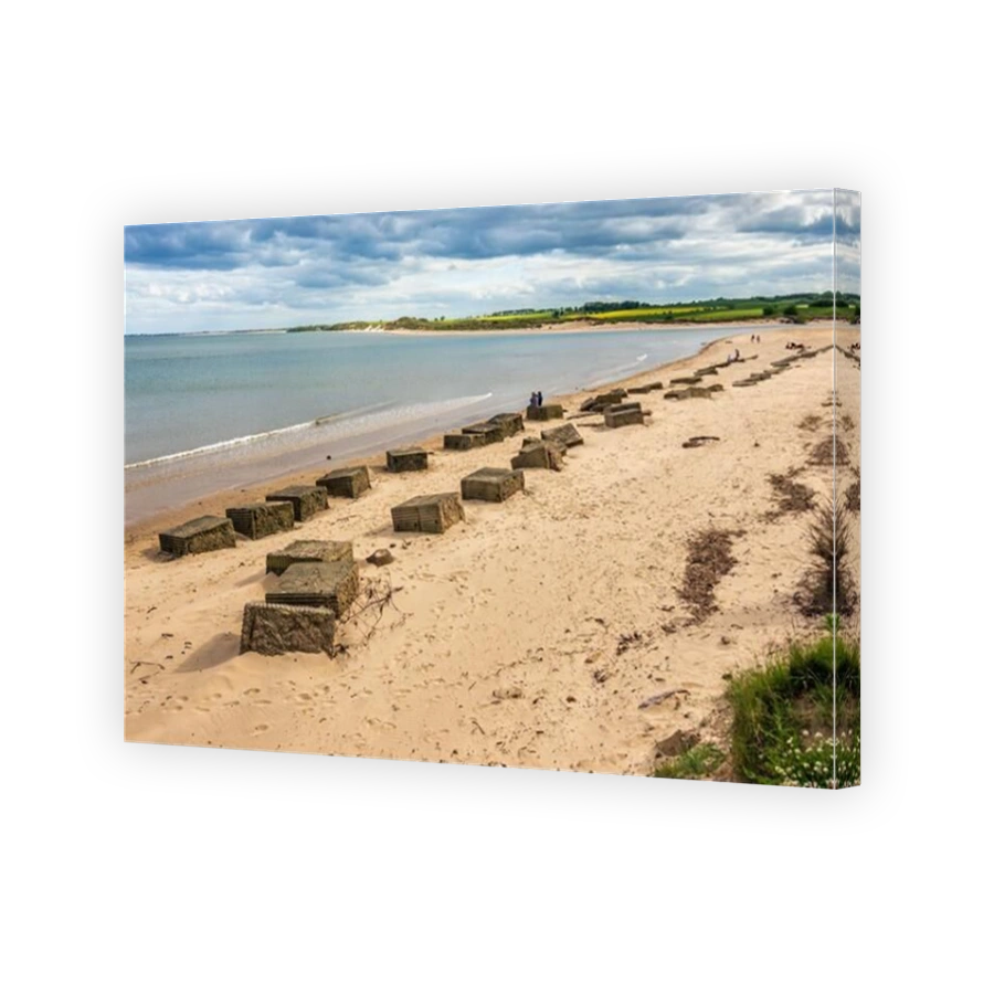 Partially buried concrete World War two anti-tank barricades remain in place over seventy five years on at Alnmouth beach in Northumberland, England