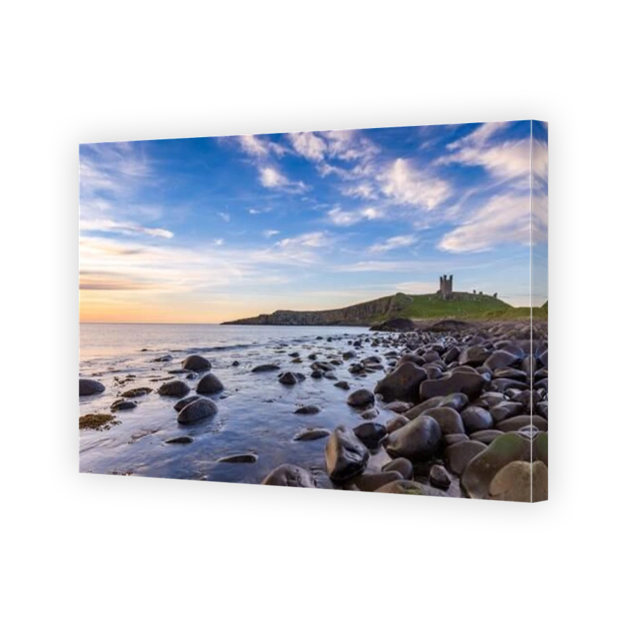 Dunstanburgh Castle at sunrise from Embleton Bay on the Northumberland coast, England, Uk