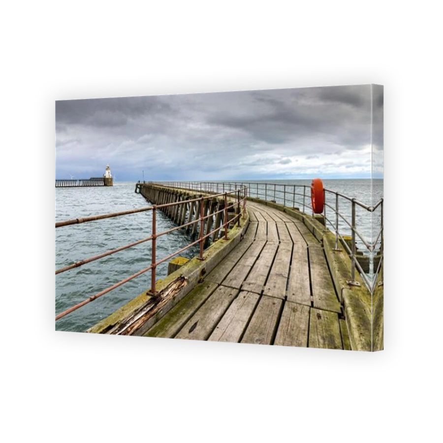 The old wooden south pier at the entrance to the Port of Blyth in Northumberland, with the pretty lighthouse on the north pier in the distance.