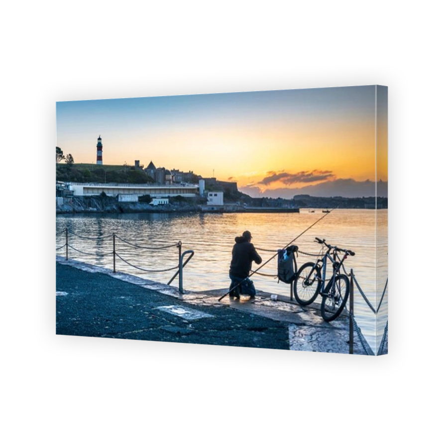 Plymouth, Devon, England. Wednesday 18th September 2019. UK Weather. After a cold night, in the first light of dawn an angler waits for a bite as the sky glows pink over Smeatons Tower on The Hoe and the harbour in Plymouth, Devon, South West England . Credit: Terry Mathews/Alamy Live News