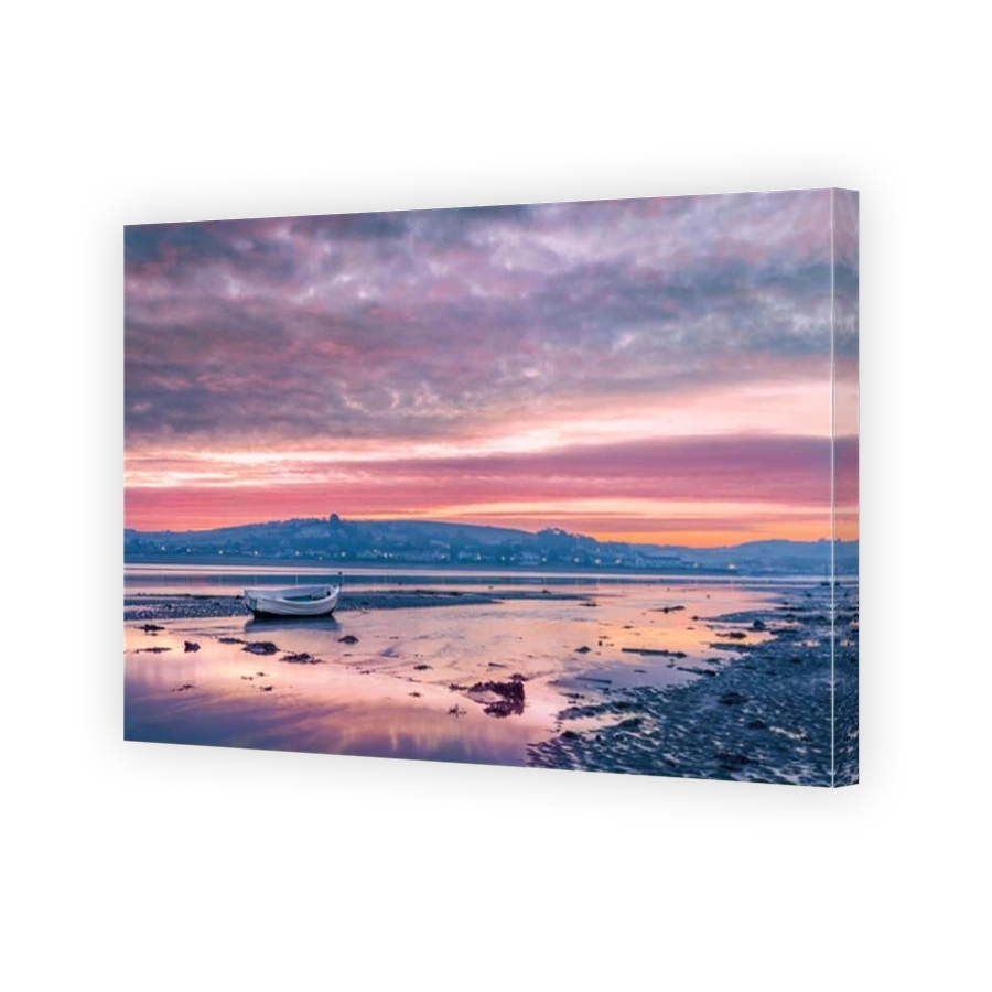 The sky reflects in the water of the incoming tide as dawn breaks over the small coastal vilage of Instow in North Devon, England.