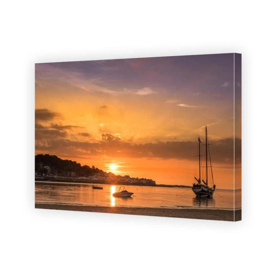 The sun sets behind the village of Appledore as the tide rolls up the beach at Instow in North Devon.