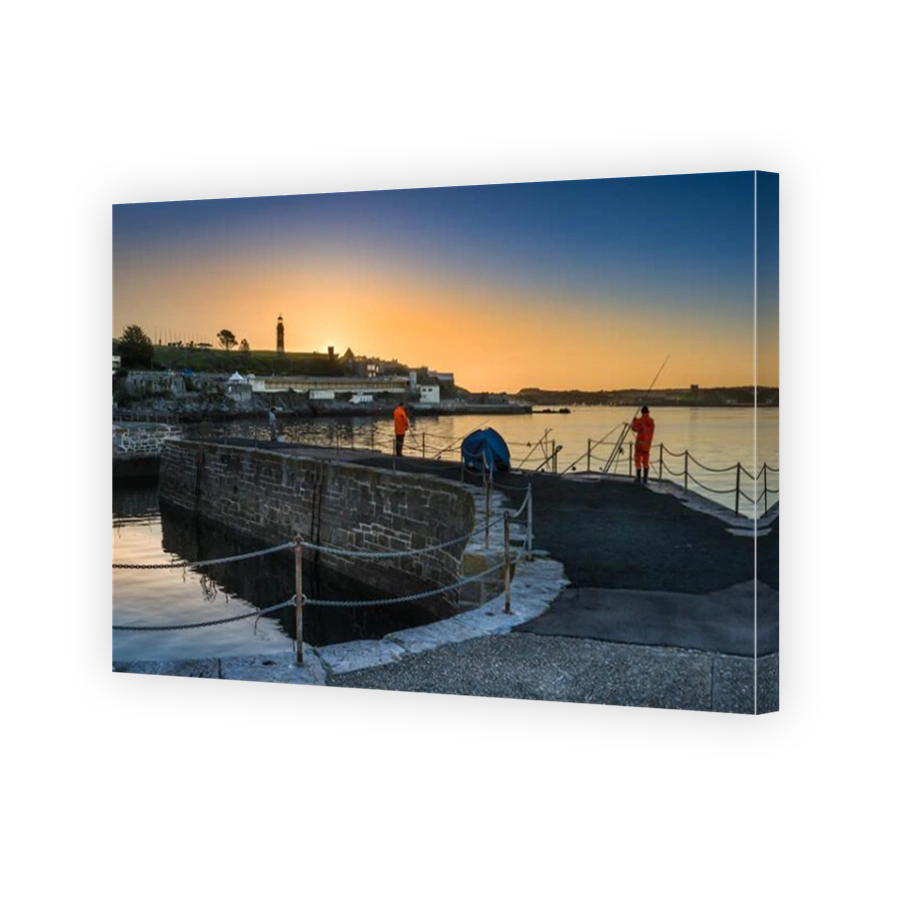 Anglers are treated to a golden sunrise on the Waterfront Harbour as the sun rises behind Smeatons Tower in Plymouth, Devon.