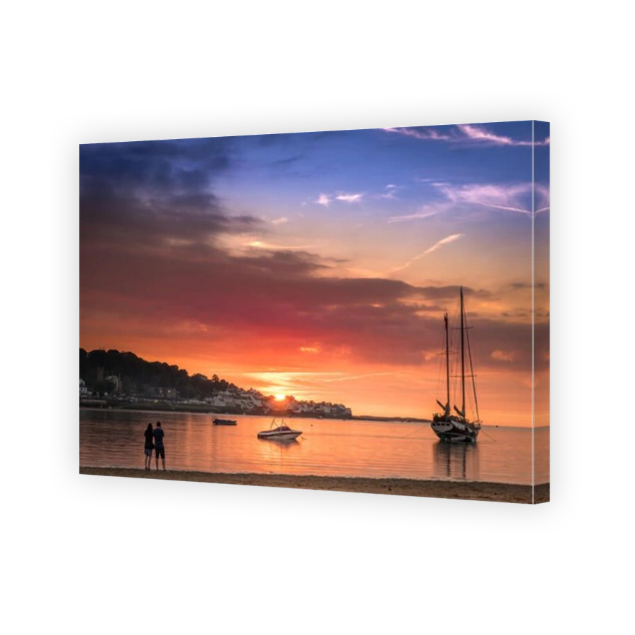 The sun sets behind the village of Appledore as the tide rolls up the beach at Instow in North Devon.