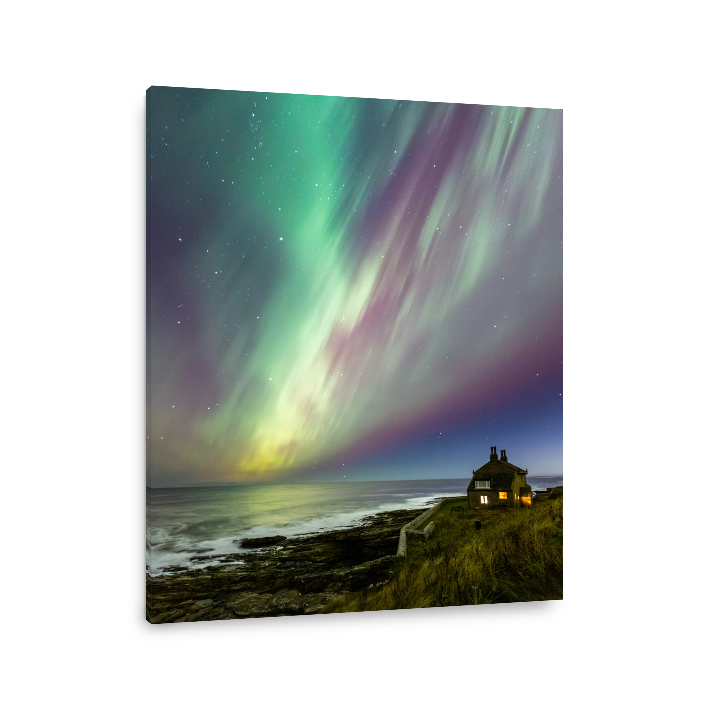 The Northern Lights over a cottage perched on cliffs overlooking the sea on the Northumberland coast during the extreme solar storm of 10th October 2024