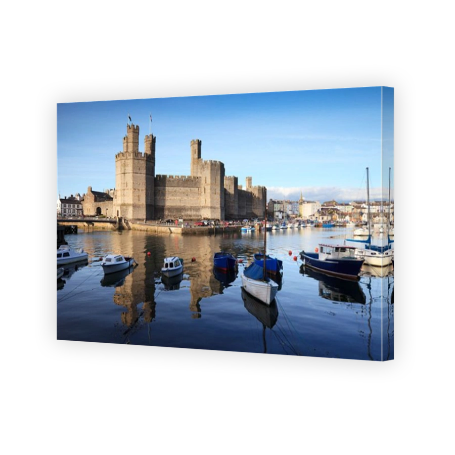 A bright summer evening at Caernarfon Castle, Gwynedd, North Wales. The castle is reflected in the River Seiont.