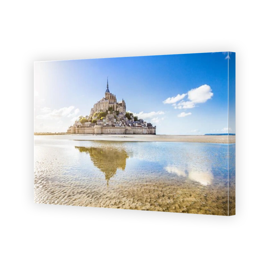 Classic view of famous Le Mont Saint-Michel tidal island on a sunny day with blue sky and clouds, Normandy, northern France