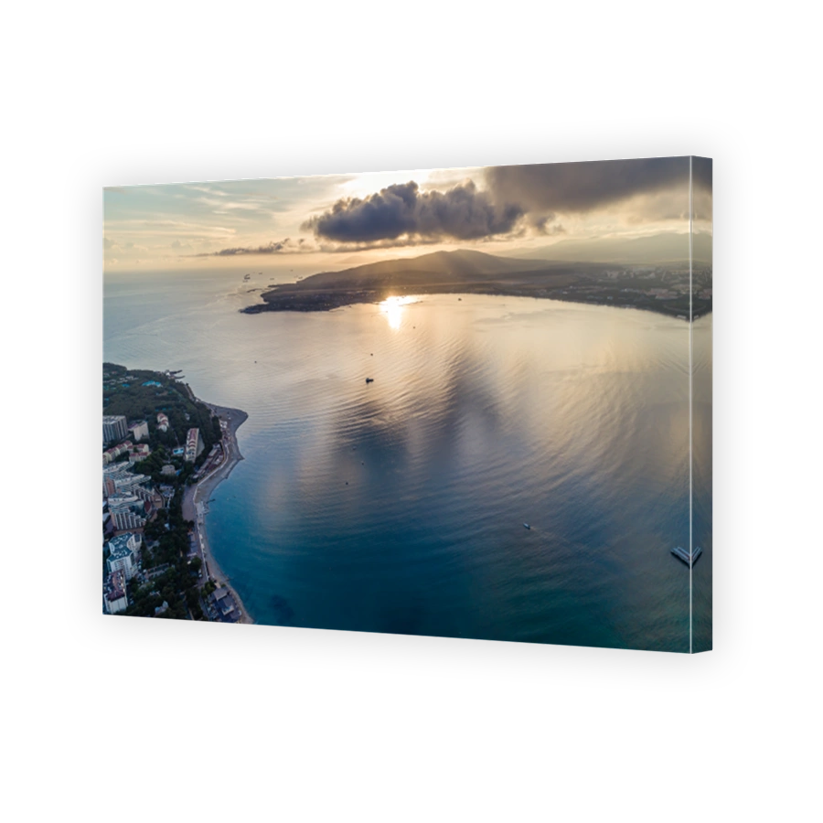 Entrance to Gelendzhik Bay at sunset. We see two capes, sun sets in clouds and is reflected in water of Gelendzhik Bay. Waves on blue water