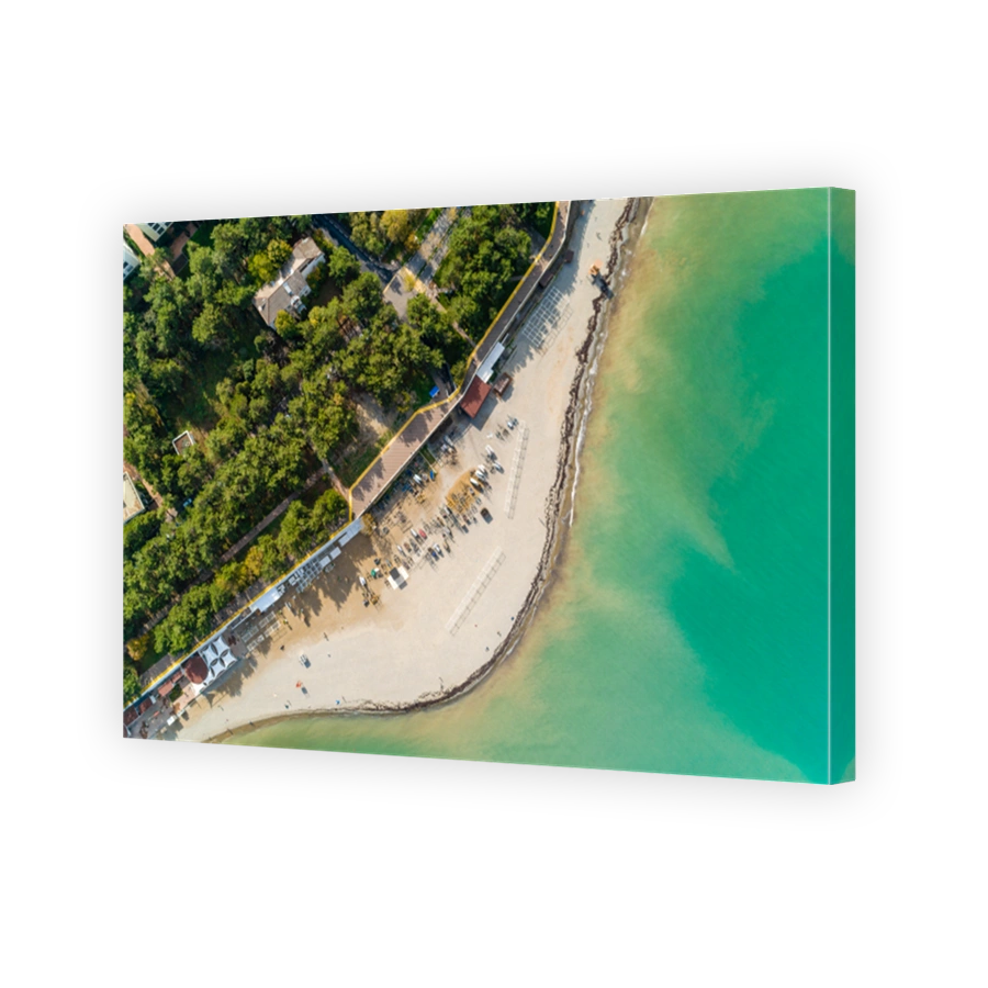 Panorama of Gelendzhik Bay on sunny day. Aerial view. Beautiful green water, lots of sails, Caucasus Mountains in background. Beach and promenade run along bay.