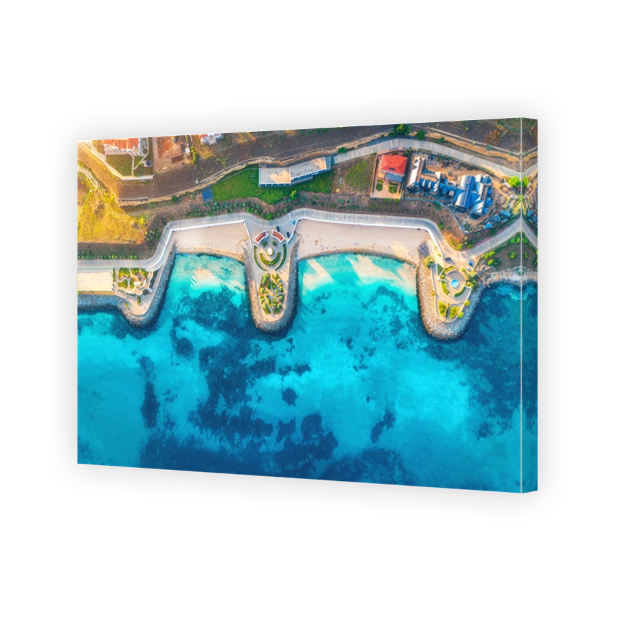 Aerial view of beautiful sandy beach, blue sea, restaurants on the promenade, pool, umbrellas, swimming people in clear water, green trees at sunset in summer. Top view of seafront. Tropical landscape